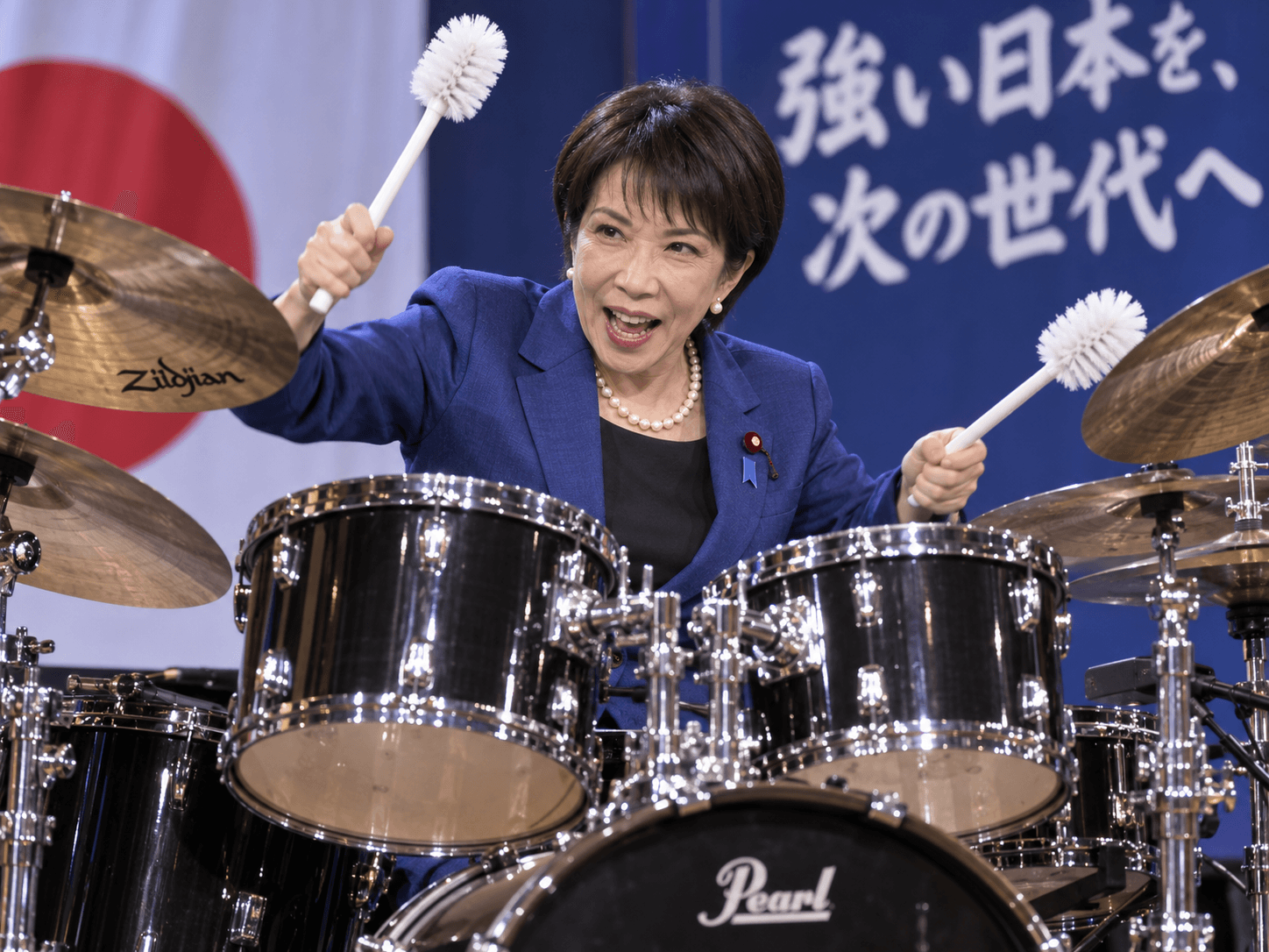 Parodic institutional image of Sanae Takaichi performing with Toilet Brushes