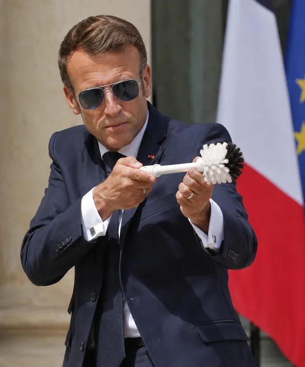 Parodic archive portrait of Emmanuel Macron presenting a Toilet Brush before the French flag